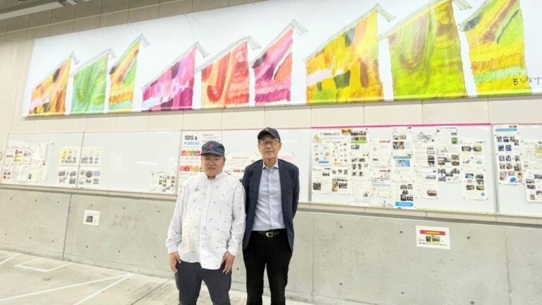 ウォールアートの前で笑顔で写真に写る藤木会長と文谷さん