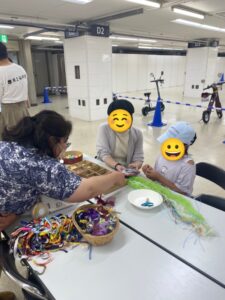 2人の子供たち作り方を教える富岡委員長（ワークショップスタッフ）