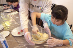 参加したお子さんが生地をこねている所、ハブラボ講師が手でボウルを持ってアシストしている