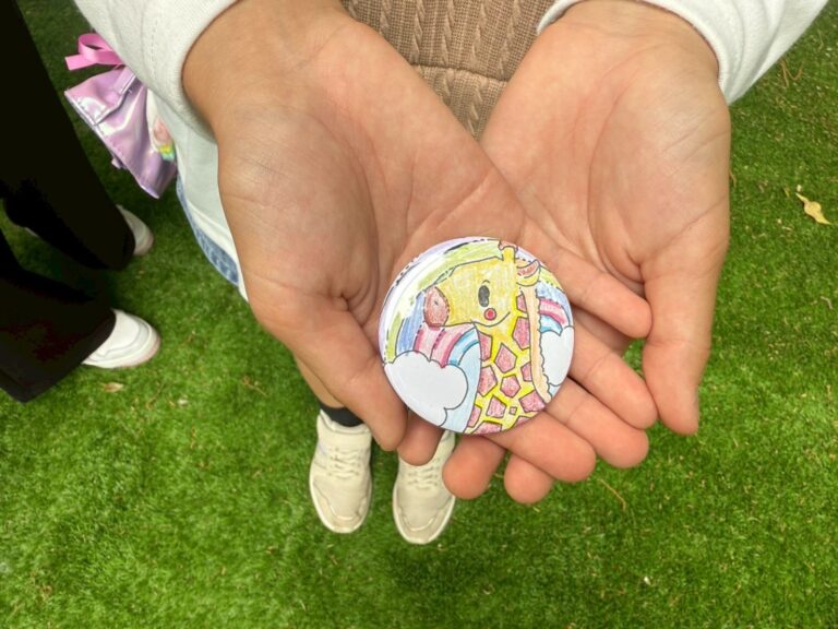 できあがった缶バッジ、キリンの線画を自分で塗った絵柄
