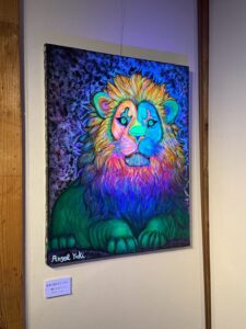 ブラックライトで照らされたアーティスト・エンジェルユキの作品。ライオンが描かれておりブラックライトで神秘的な雰囲気になっている