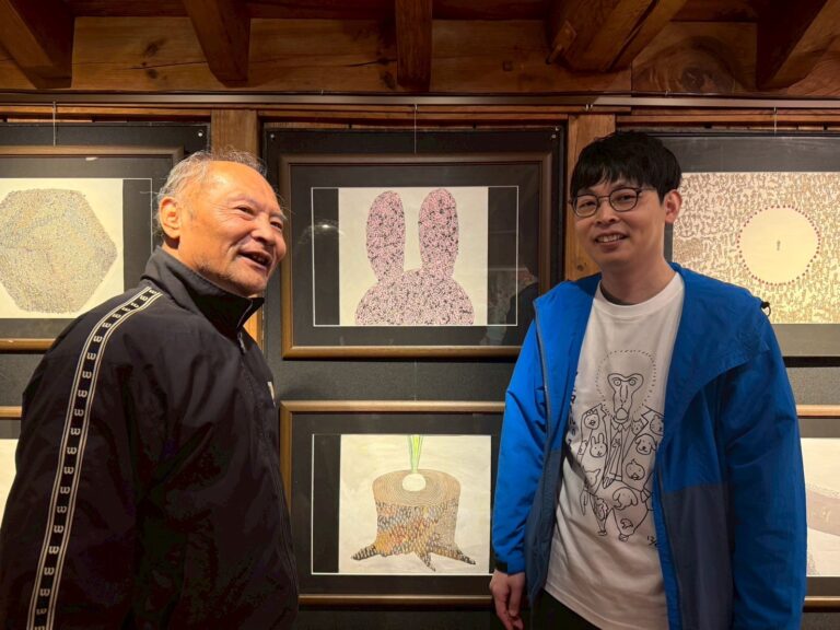 自分の作品の前で館長田村さんと写るアーティスト・りょう