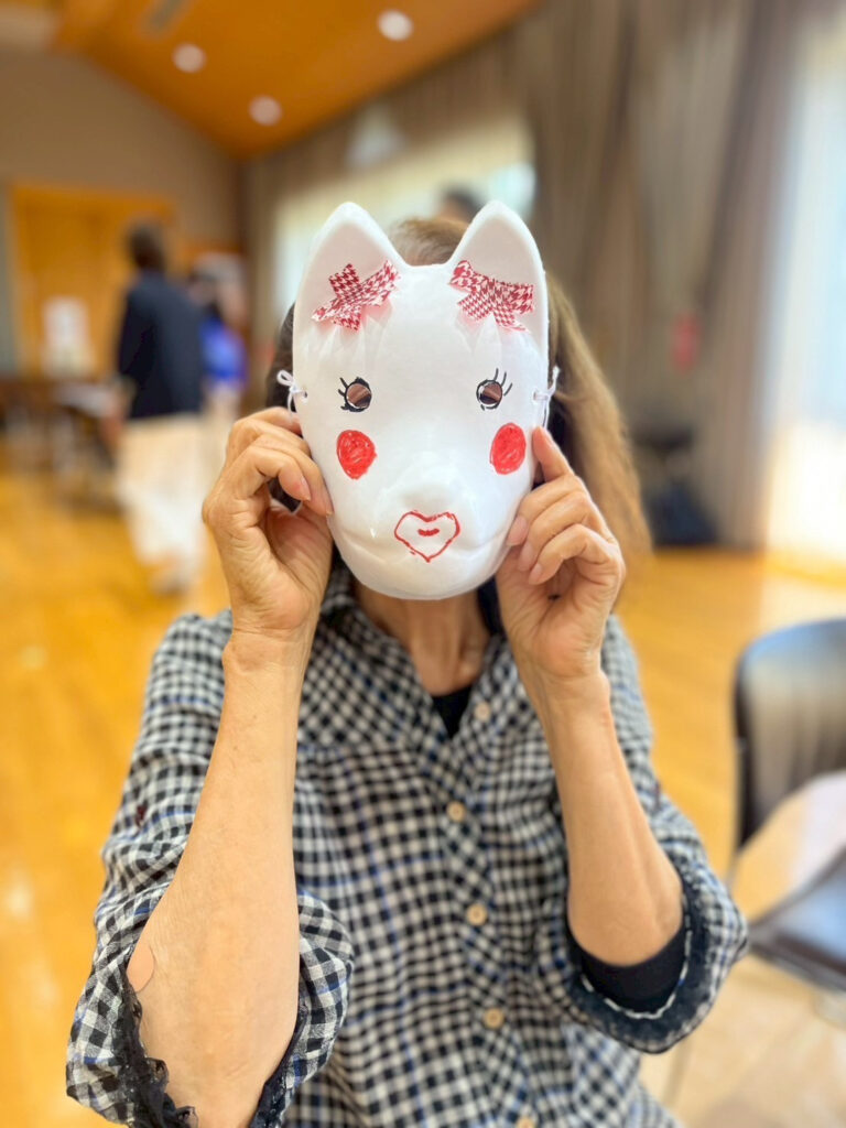 参加者の方ができあがったお面を顔の前に置いて記念撮影