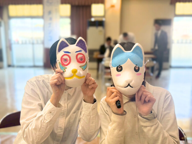 参加者2人組の方ができあがったお面を顔の前に置いて記念撮影