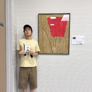 絵の前でサンクスカードを持ってうつる伊藤士隼