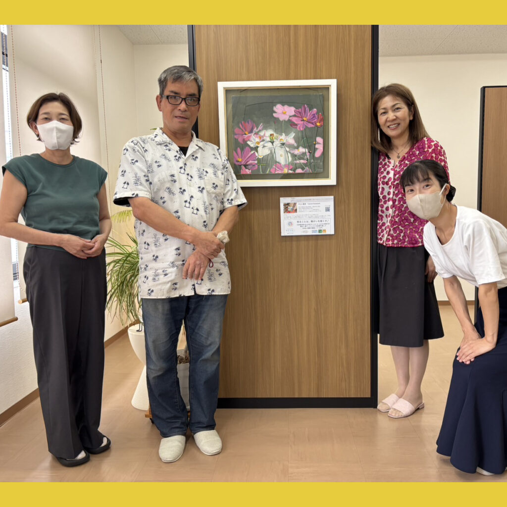 納品した作品の前で笑顔で写るアーティスト・川上岳史と中川事務所の方3名。