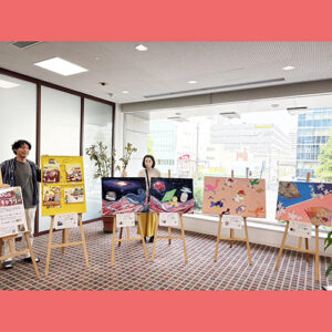 納品した作品が並んでいる横や後ろに立つアーティスト・miyaとアーティスト・小林智恵子