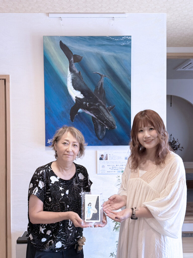 納品した作品の前で笑顔で写るアーティスト・Rieと株式会社スパーキーの方