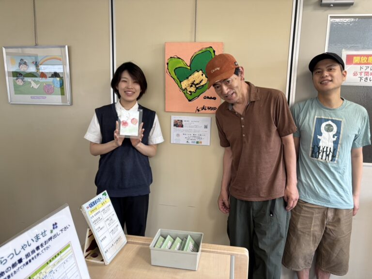 納品した作品「グリーンハート」の前に立っている コーホク印刷の方（左）アーティスト・橋本賢二（中央）、アーティスト・伊藤士隼（右）