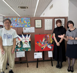 納品した作品の前で笑顔で写るアーティスト・土肥ヨシ、アーティスト・Rie、岡山トヨタの方