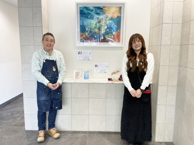 納品した作品の前で笑顔で写るアーティスト・下村良作とアーティスト・Rie