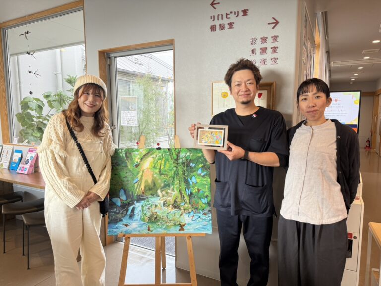 納品した作品を囲んで写るアーティスト・Rie（左）、小野内科医院の方２名（右）