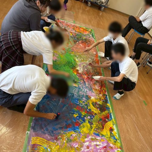 １ｍ×２ｍの大きな紙に自由に絵を描く東支援学校の生徒たちとアーティストしゃけ。