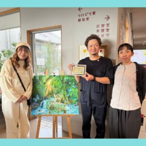 納品した作品を囲んで写るアーティスト・Rie（左）、小野内科医院の方２名（右）
