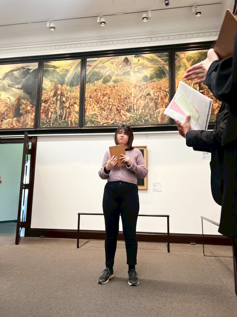 大きな絵の前で作った俳句を詠むメンバー・よっしー