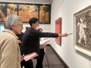 アーティスト・土肥ヨシと、ポロック作「カットアウト」を指さして彼に何かを話している副社長・馬場