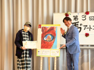 賞状を手に持ったアーティスト・ユメサキハル（左）と主催団体の方（右）