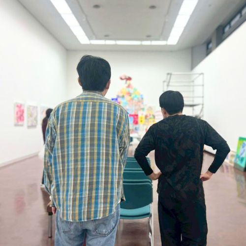 できあがったアーティスト・りょう展示を見ているりょうともう一方の後ろ姿