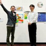 作品の前2人で写るパートナー企業の方(左・右腕を大きく広げている)とアーティスト・Miya(右・前で腕をそろえている) お笑い芸人が漫才をしているような構図