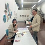 アーティスト・かなっぺ(左)と受け取ったサンクスカードをもって写るパートナー企業の方(右)