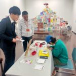 サンクスカードを描くアーティストKAITO(右)と完成を待つパートナー企業の方(左)