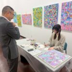 パートナー企業の方(左)と話しながらサンクスカードを制作するアーティスト・かなっぺ(右)