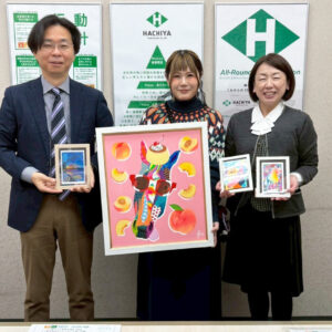 蜂谷工業のお二方（左右）と手に納品した作品を持ったアーティスト・Rie（中央）