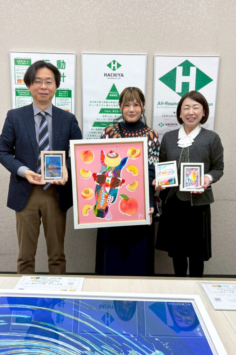 蜂谷工業のお二方（左右）と手に納品した作品を持ったアーティスト・Rie（中央）