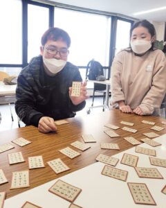 取った札をもって笑顔のたっくん、右隣りにミポリン