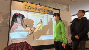 グランプリの表彰状を読み上げるろりちゃん(左)とそれを聞いているさきちゃん&奥野マネージャー(右)