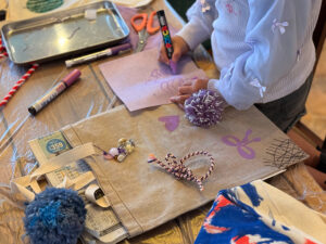 グレーのトートバッグにリボンを描いたり、ひもでリボンをつくってくっつけている